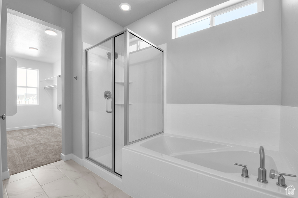 Full bathroom with a bath, a shower stall, and baseboards