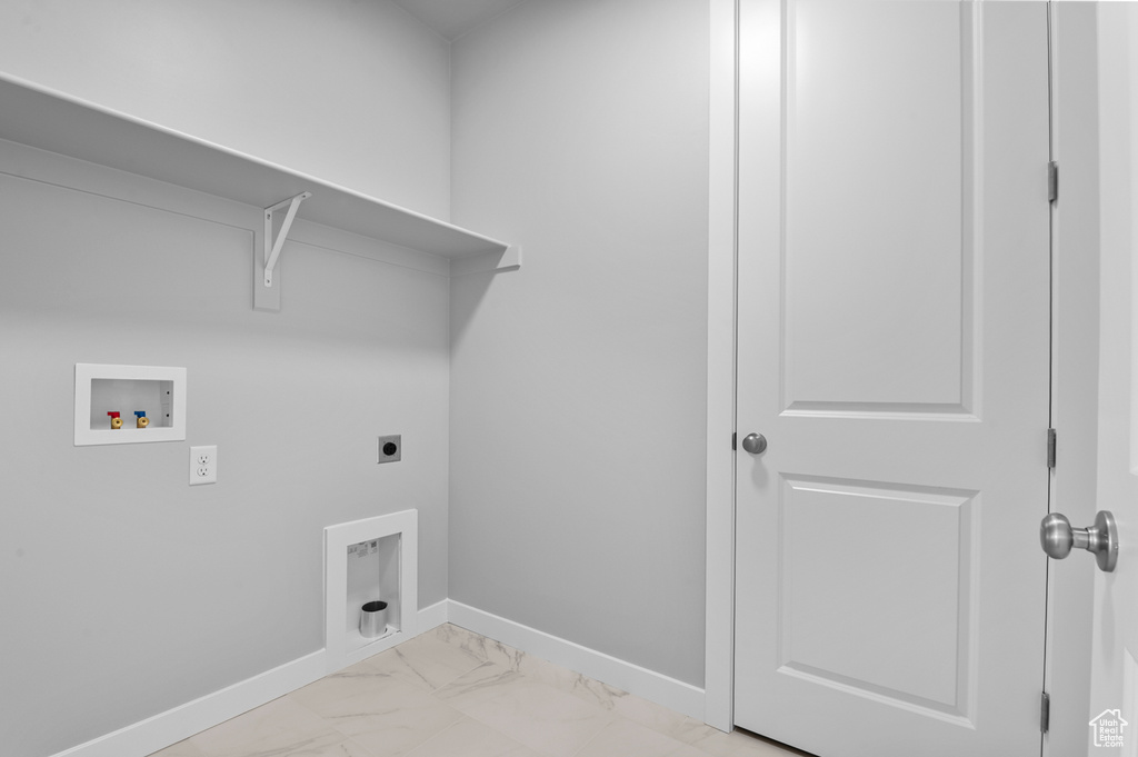 Laundry area with electric dryer hookup, hookup for a washing machine, baseboards, and light marble finish floors