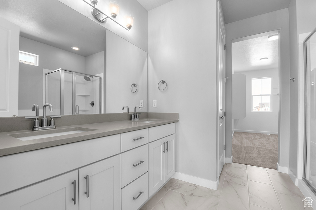Full bath featuring double vanity, a stall shower, plenty of natural light, and baseboards