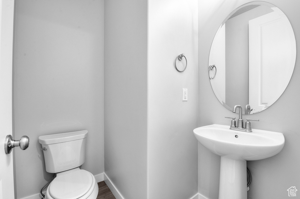 Half bath featuring toilet, baseboards, and wood finished floors