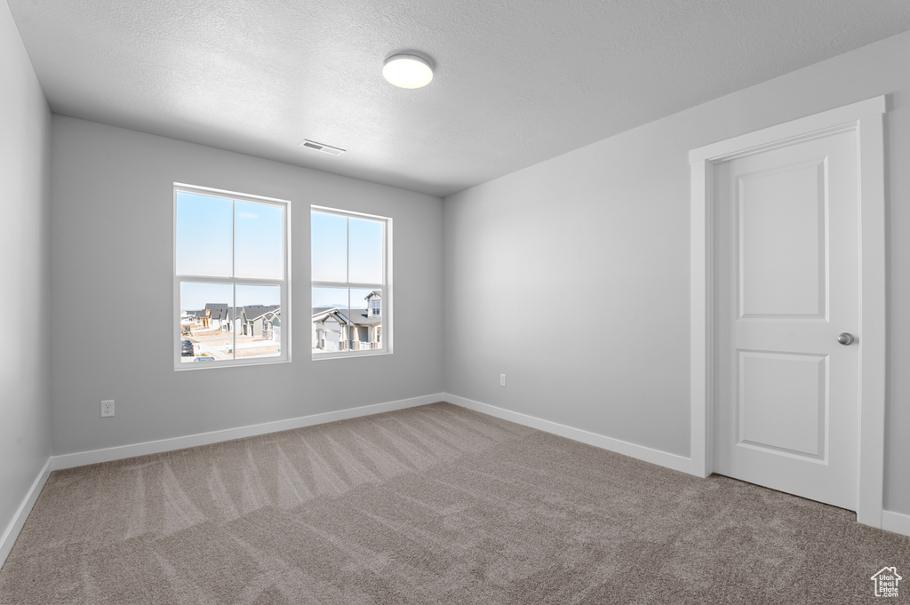Unfurnished room with carpet floors, baseboards, and a textured ceiling
