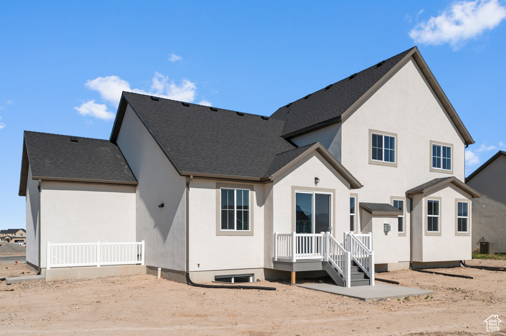 Back of house with stucco siding, roof with shingles, and central air condition unit