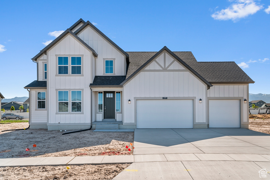 View of front of property with a garage, roof with shingles, driveway, board and batten siding, and a mountain view
