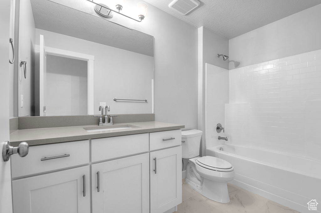 Full bathroom featuring toilet, vanity, shower / bathtub combination, marble look tiles, and a textured ceiling