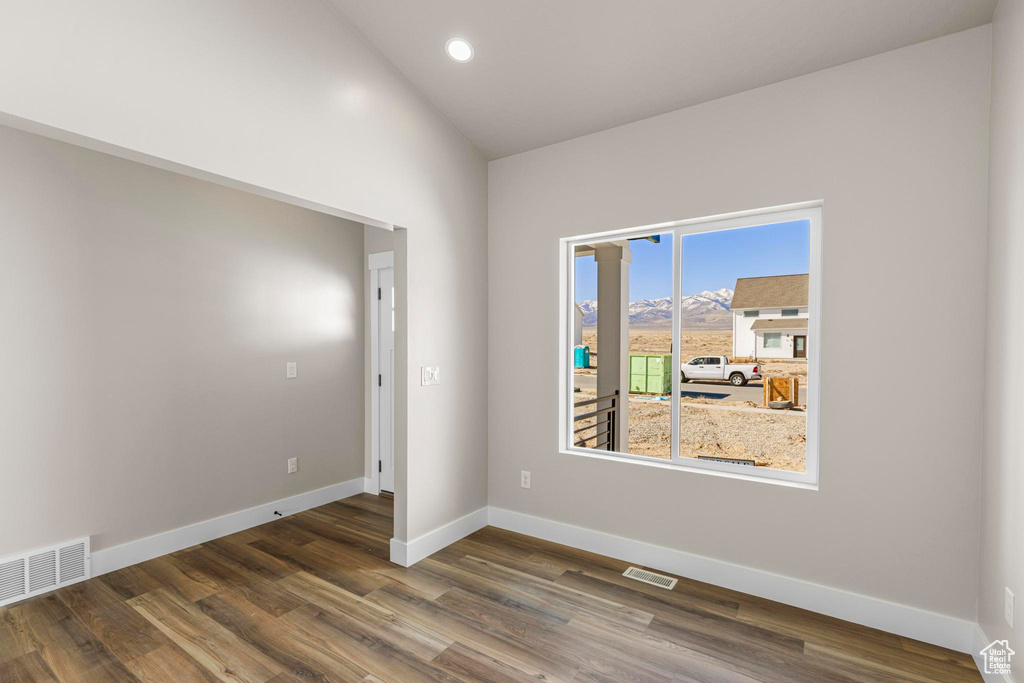 Empty room featuring baseboards, visible vents, lofted ceiling, dark wood-type flooring, and recessed lighting