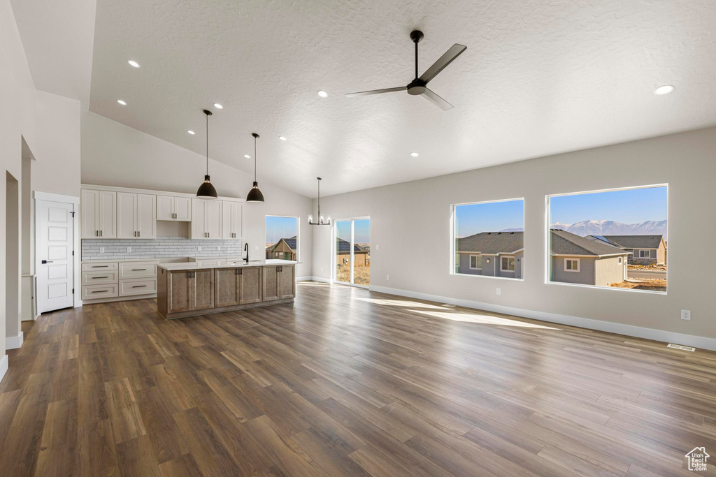 Kitchen with a kitchen island with sink, dark wood-style flooring, white cabinets, open floor plan, and decorative backsplash