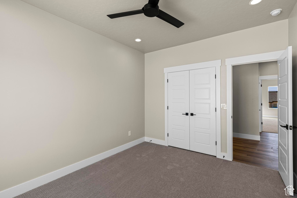 Unfurnished bedroom with dark colored carpet, a closet, recessed lighting, a ceiling fan, and baseboards