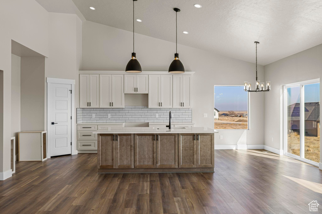 Kitchen featuring dark wood-style floors, white cabinetry, a sink, and tasteful backsplash