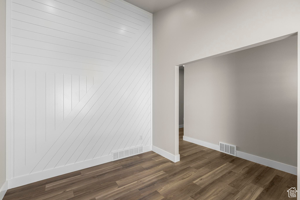 Spare room with dark wood-type flooring, visible vents, and baseboards