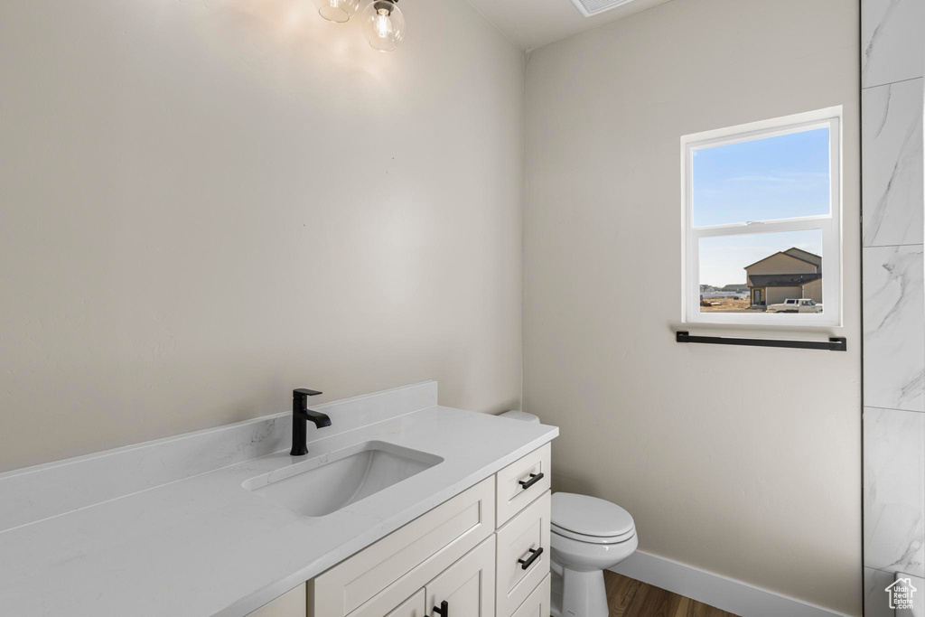 Bathroom with baseboards, vanity, toilet, and wood finished floors