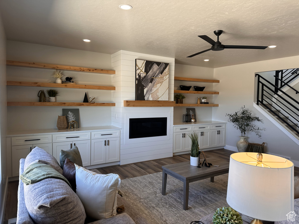 Living room featuring dark wood-style flooring, stairway, ceiling fan, recessed lighting, and a textured ceiling