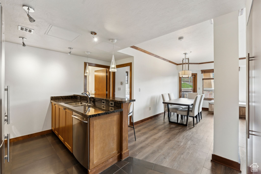Kitchen with a sink, stainless steel dishwasher, baseboards, and crown molding