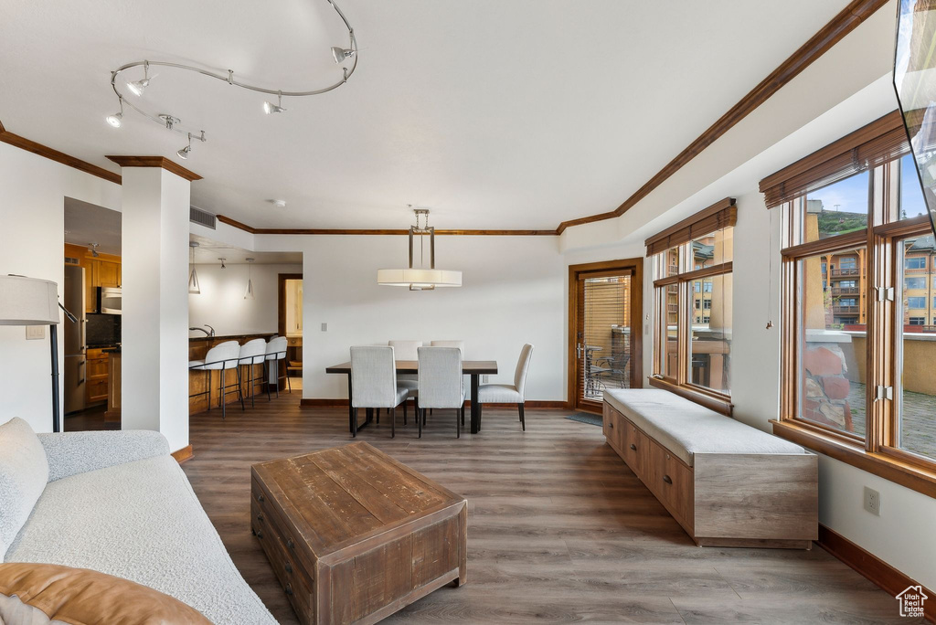 Living area featuring wood finished floors, baseboards, and crown molding