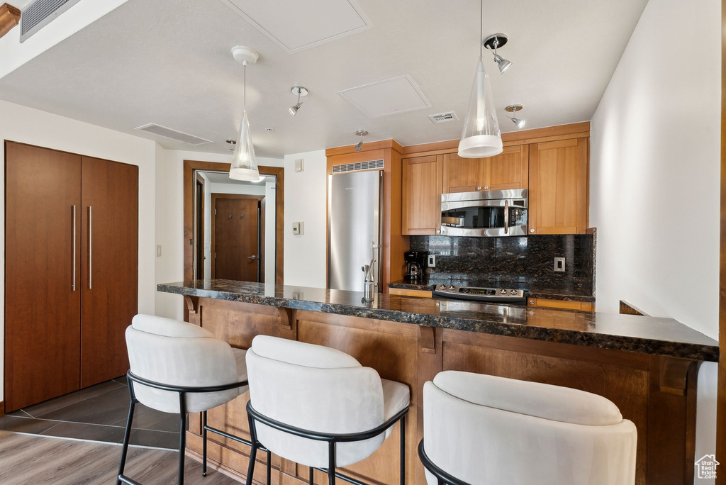 Kitchen featuring stainless steel appliances, tasteful backsplash, a breakfast bar, and hanging light fixtures