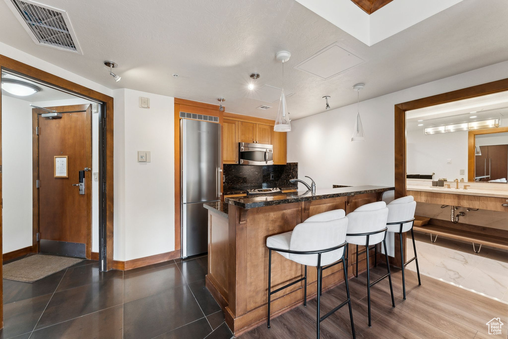 Kitchen featuring appliances with stainless steel finishes, a breakfast bar area, tasteful backsplash, baseboards, and a sink
