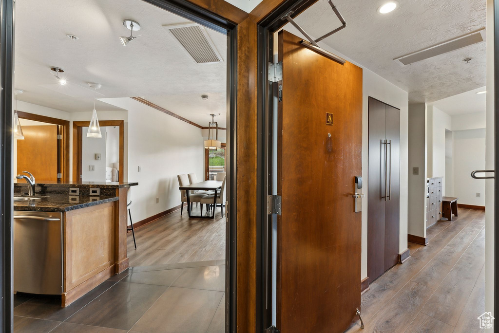 Hallway featuring baseboards, dark wood-type flooring, a sink, and recessed lighting