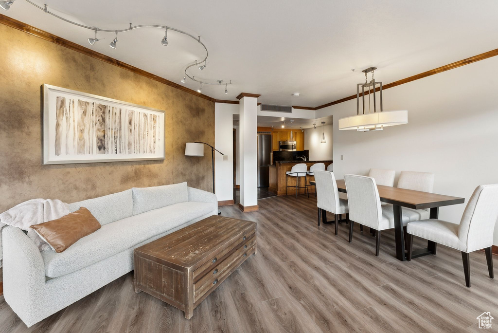 Living area featuring ornamental molding, wood finished floors, rail lighting, and baseboards