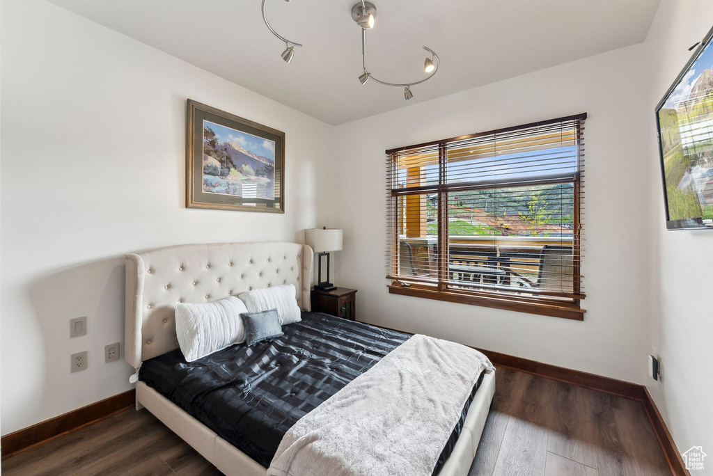 Bedroom with multiple windows, baseboards, and wood finished floors