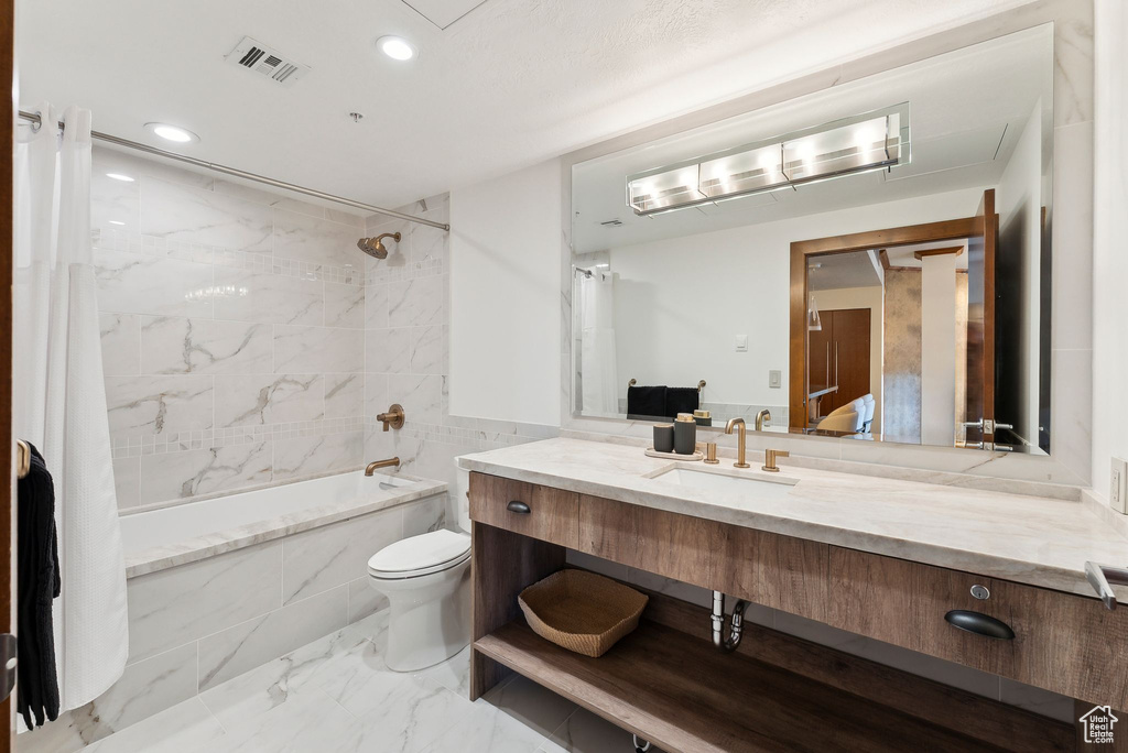 Full bath with shower / bathtub combination, toilet, marble look tile flooring, vanity, and recessed lighting