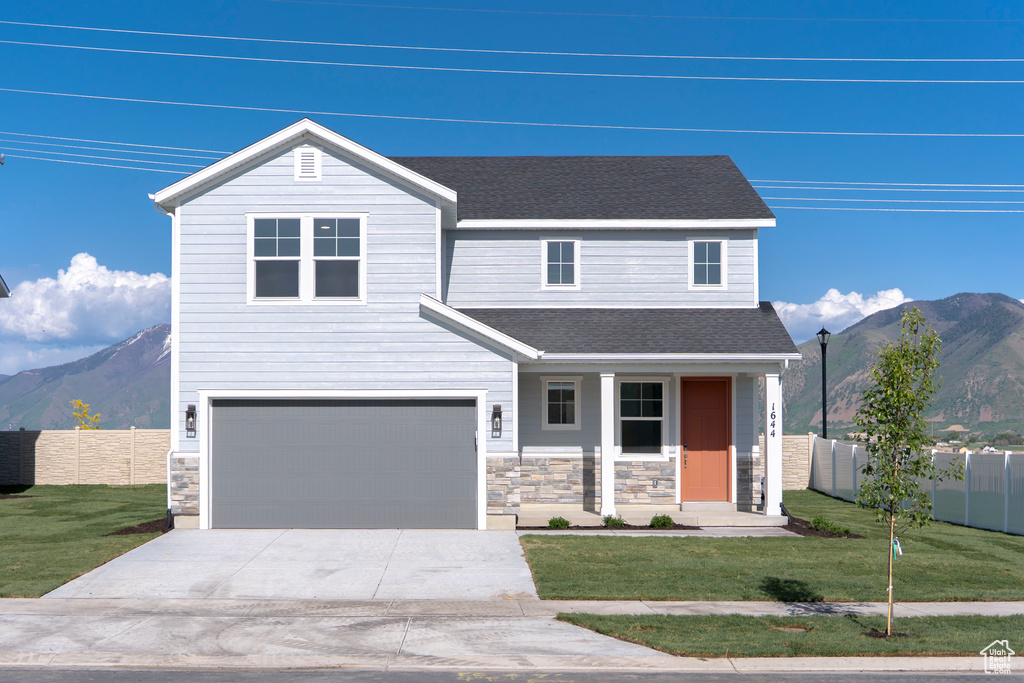 View of front of property with a mountain view, concrete driveway, stone siding, a garage, and covered porch