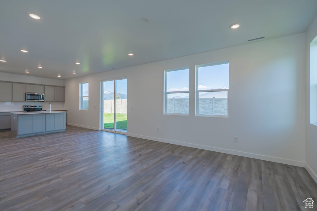Unfurnished living room with baseboards, wood finished floors, and recessed lighting