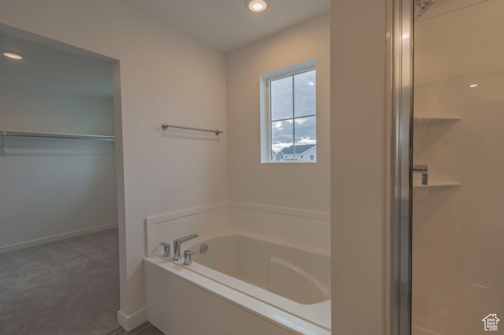 Bathroom featuring a garden tub, baseboards, recessed lighting, and a spacious closet