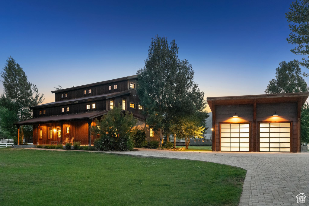 View of front of property featuring a lawn, a garage, driveway, an outdoor structure, and a porch