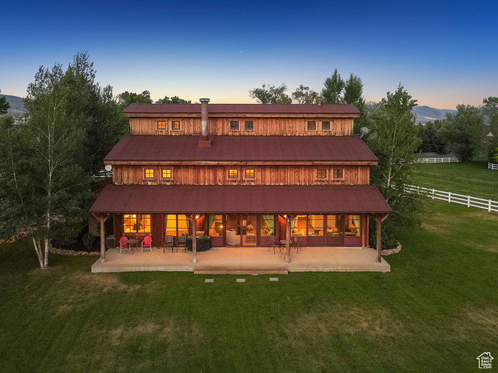 Back of property at dusk with a patio and a mountain view