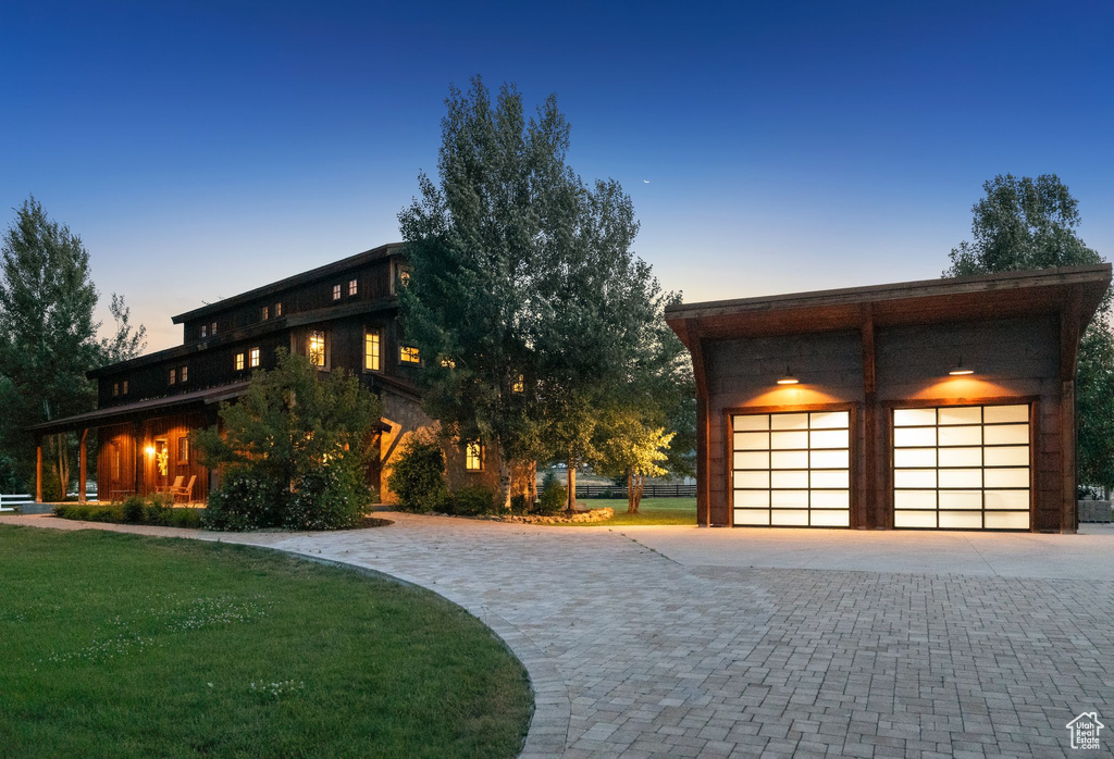 View of front of house with decorative driveway, an outbuilding, and a front lawn