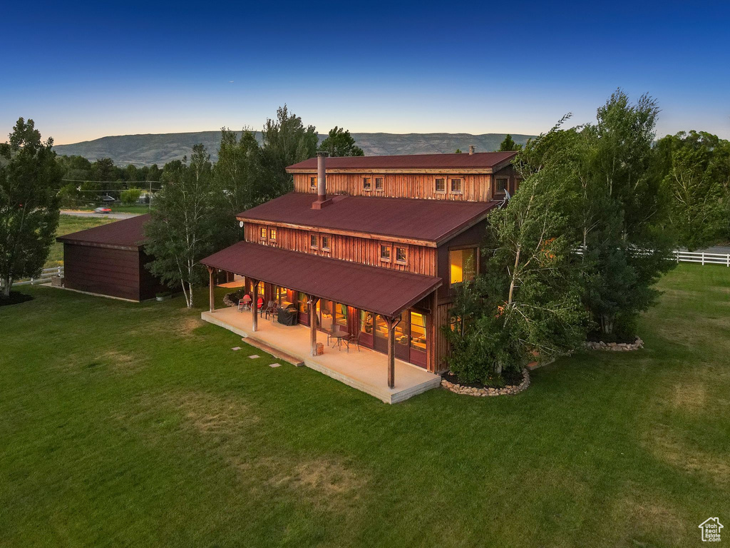Back of property featuring a patio, a mountain view, and a metal roof