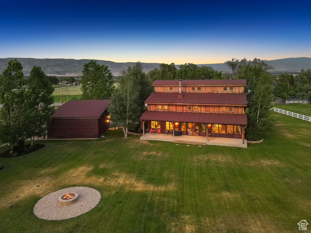 Back of house at dusk with a patio, a mountain view, and an outbuilding