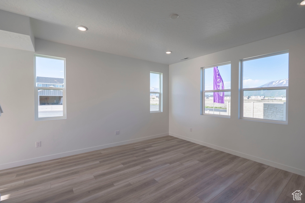 Empty room featuring light wood-type flooring, baseboards, and recessed lighting