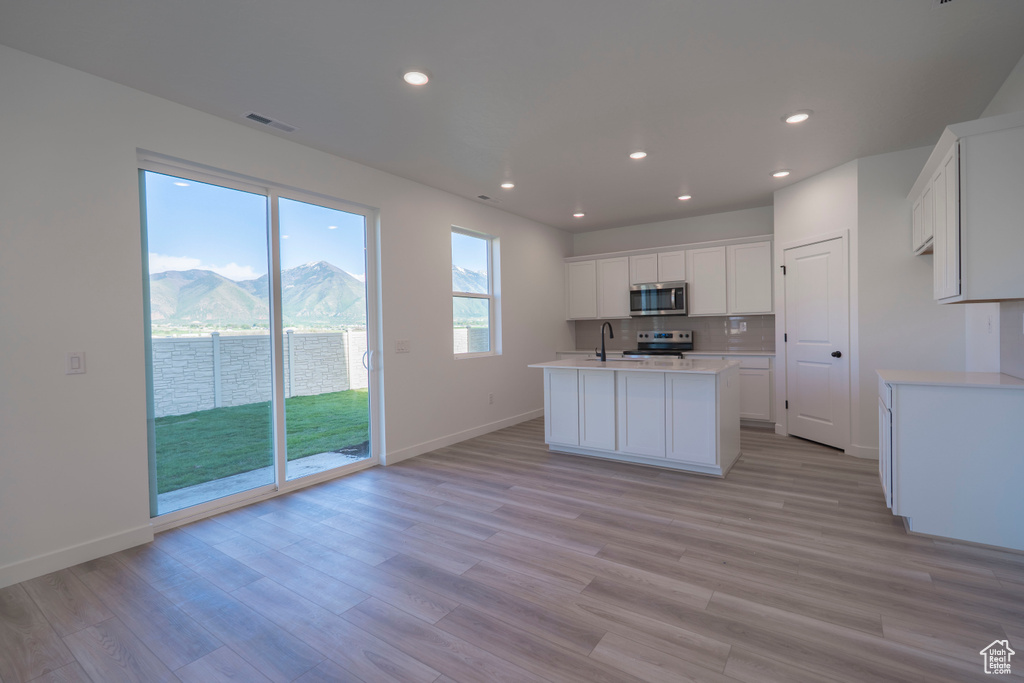 Kitchen with stainless steel appliances, light countertops, baseboards, recessed lighting, and light wood-type flooring