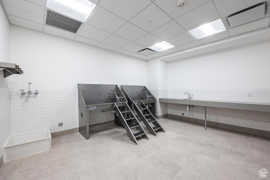 Misc room featuring a paneled ceiling and tile walls