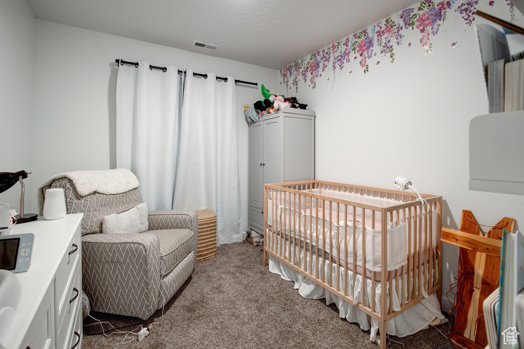 Bedroom with carpet floors, a nursery area, and visible vents