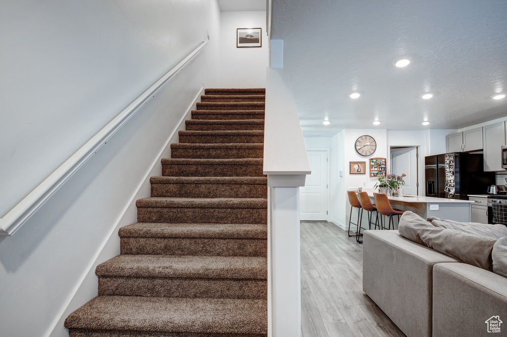 Stairs with baseboards, wood finished floors, and recessed lighting