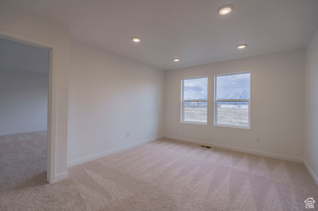 Empty room featuring light colored carpet, baseboards, and recessed lighting