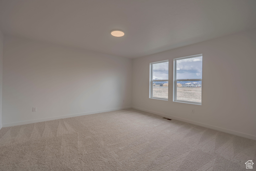 Empty room featuring light carpet and baseboards