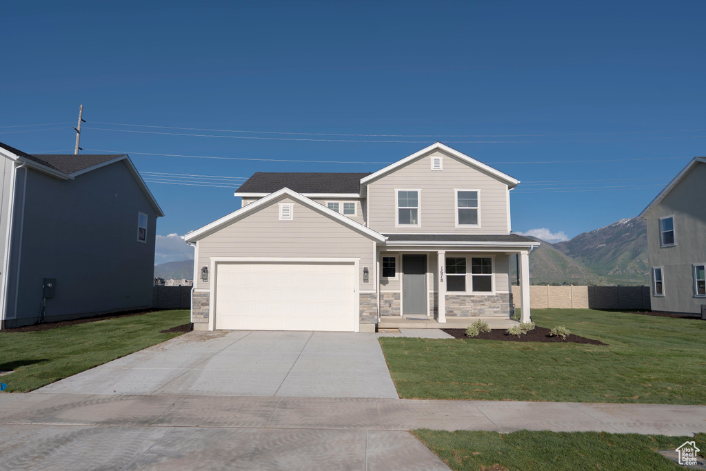 View of front of property with covered porch, driveway, an attached garage, stone siding, and a mountain view