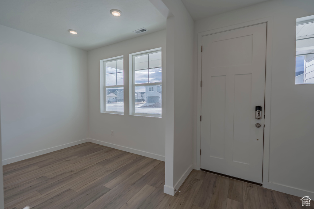 Foyer entrance with healthy amount of natural light, light wood finished floors, baseboards, and recessed lighting