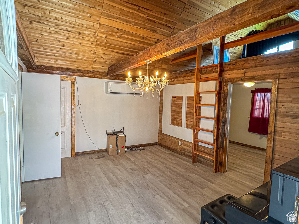 Unfurnished room featuring beamed ceiling, a wood stove, hardwood / wood-style flooring, a notable chandelier, and wood ceiling