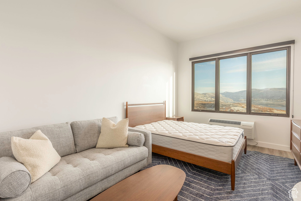 Bedroom featuring baseboards, wood finished floors, vaulted ceiling, a mountain view, and a wall mounted AC
