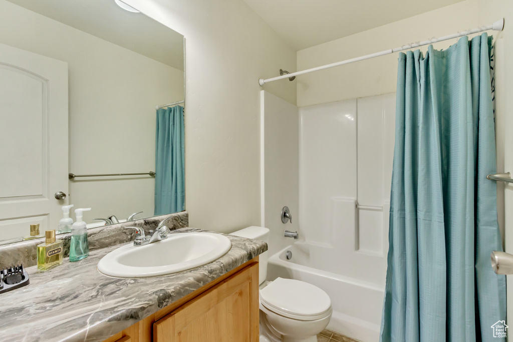 Bathroom featuring toilet, shower / bath combination with curtain, and vanity