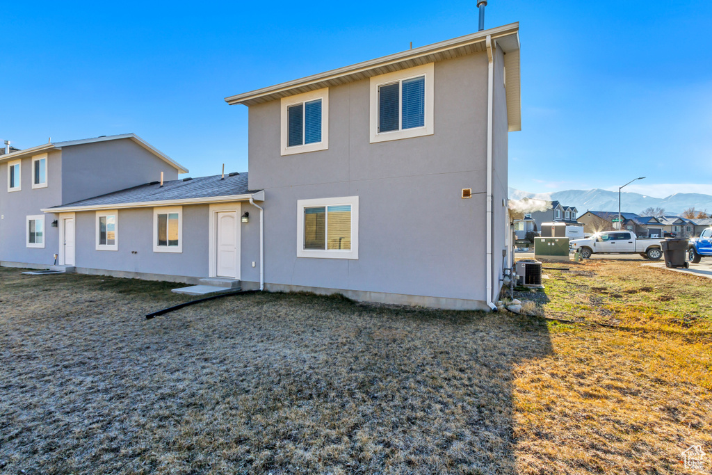 Rear view of property featuring central air condition unit, a mountain view, and stucco siding