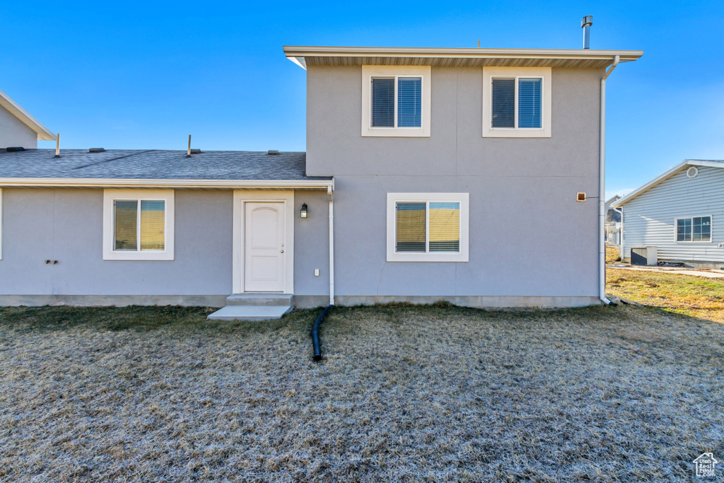 Back of property with roof with shingles and stucco siding