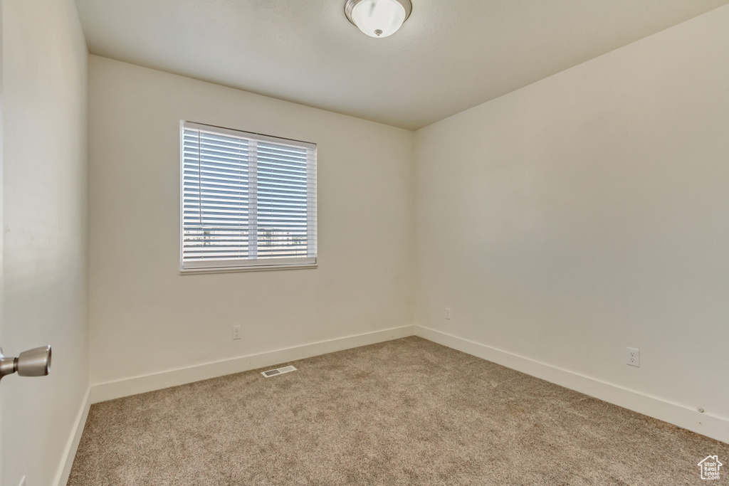 Unfurnished room featuring light carpet, visible vents, and baseboards