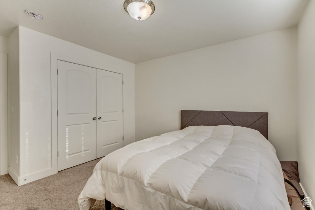 Bedroom with light carpet and a closet