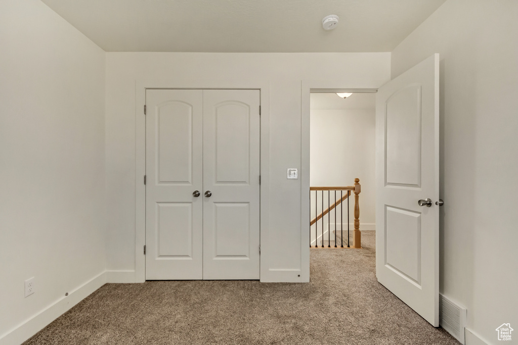 Unfurnished bedroom with light carpet, visible vents, baseboards, and a closet