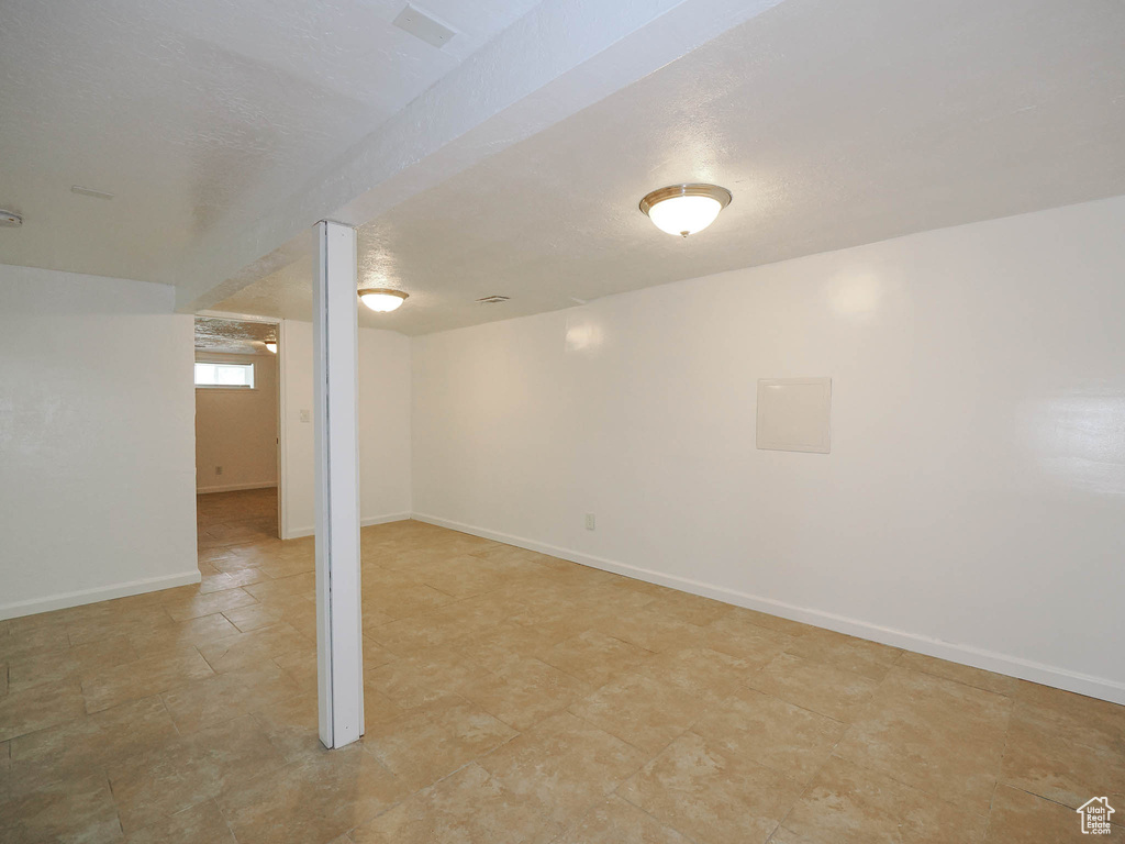 Below grade area with a textured ceiling and baseboards