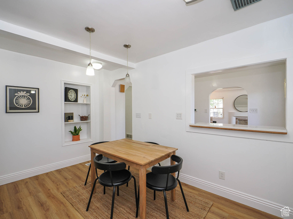Dining area with visible vents, baseboards, arched walkways, built in features, and light wood-style floors